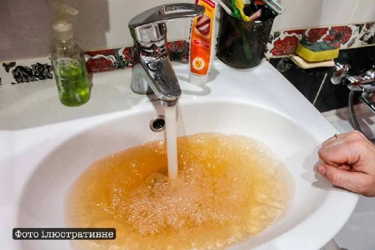Вода жовтого кольору тече з крана в раковину