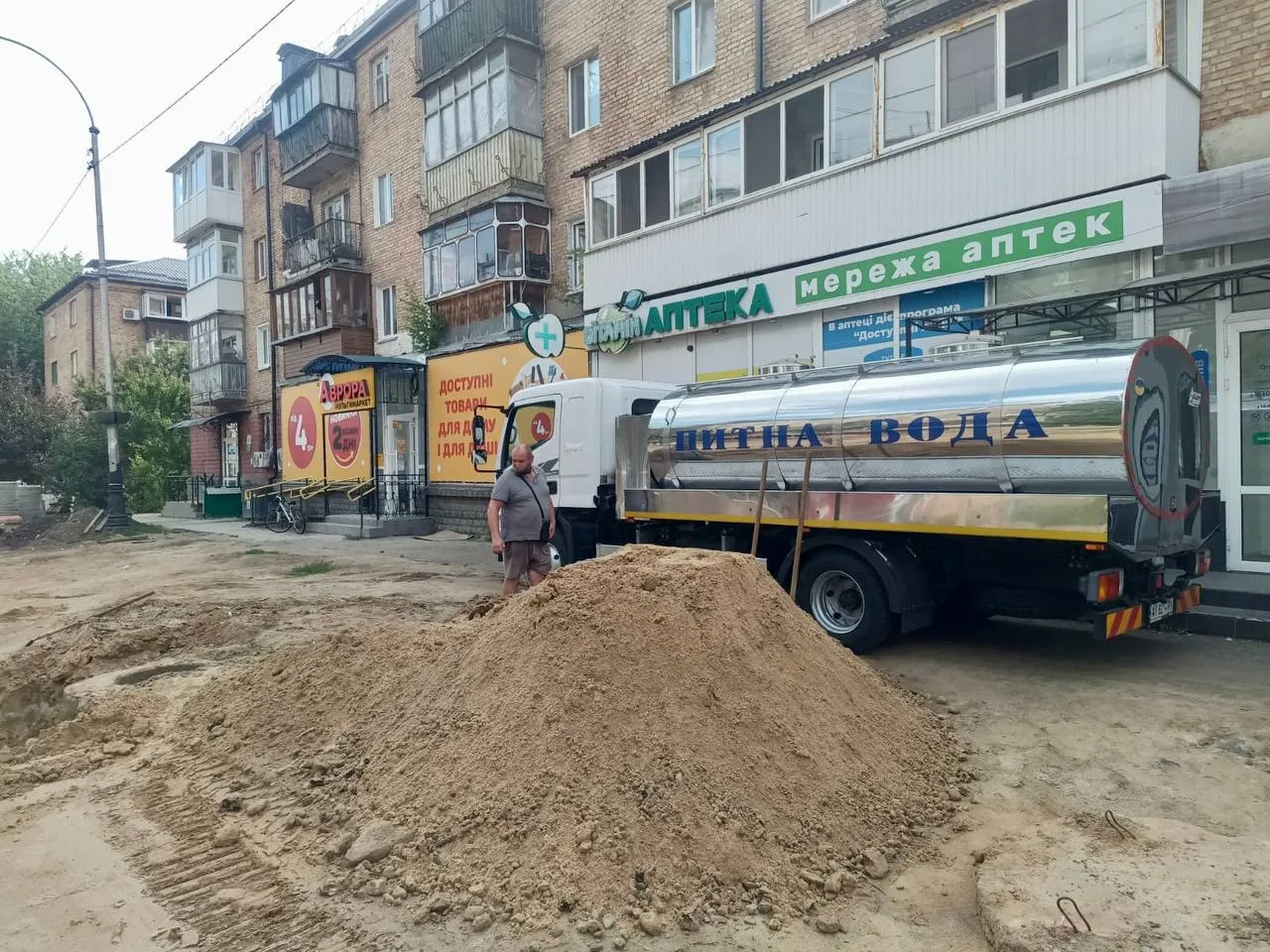 Цистерна з водою біля купи піску на вулиці міста