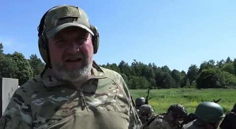Чоловік у військовому камуфляжі та кепці на відкритій місцевості