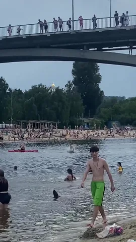 Люди купаються в річці під мостом з глядачами