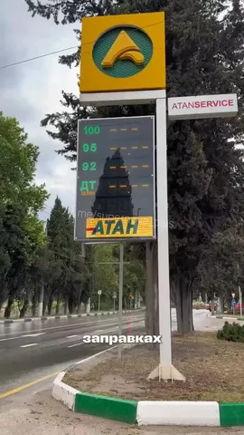 Дорожний знак АЗС на вулиці з деревами