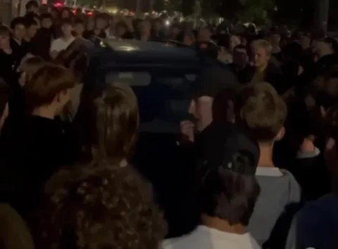 Натовп людей навколо автомобіля вночі на вулиці