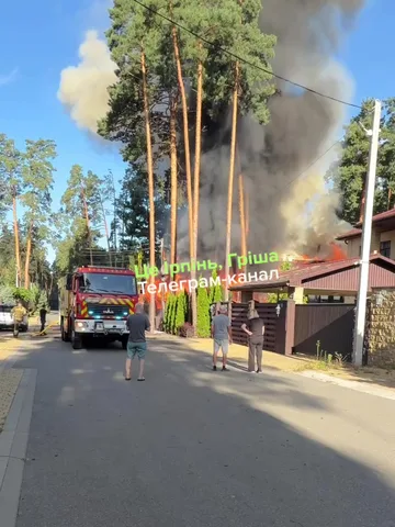Пожежна машина біля палаючого будинку серед дерев