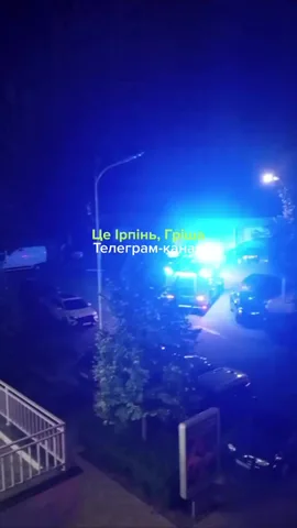Нічна вулиця з включеними ліхтарями та машинами екстрених служб