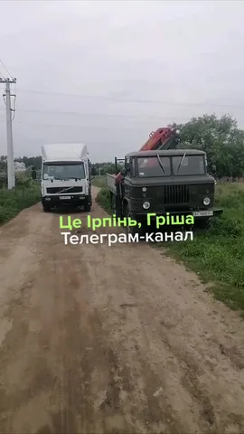 Два вантажні автомобілі на грунтовій дорозі біля електроопори