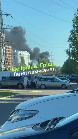 Дим над будівлями в Ірпені біля припаркованих автомобілів