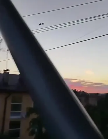 Вертоліт у небі над житловою забудовою на сутінках