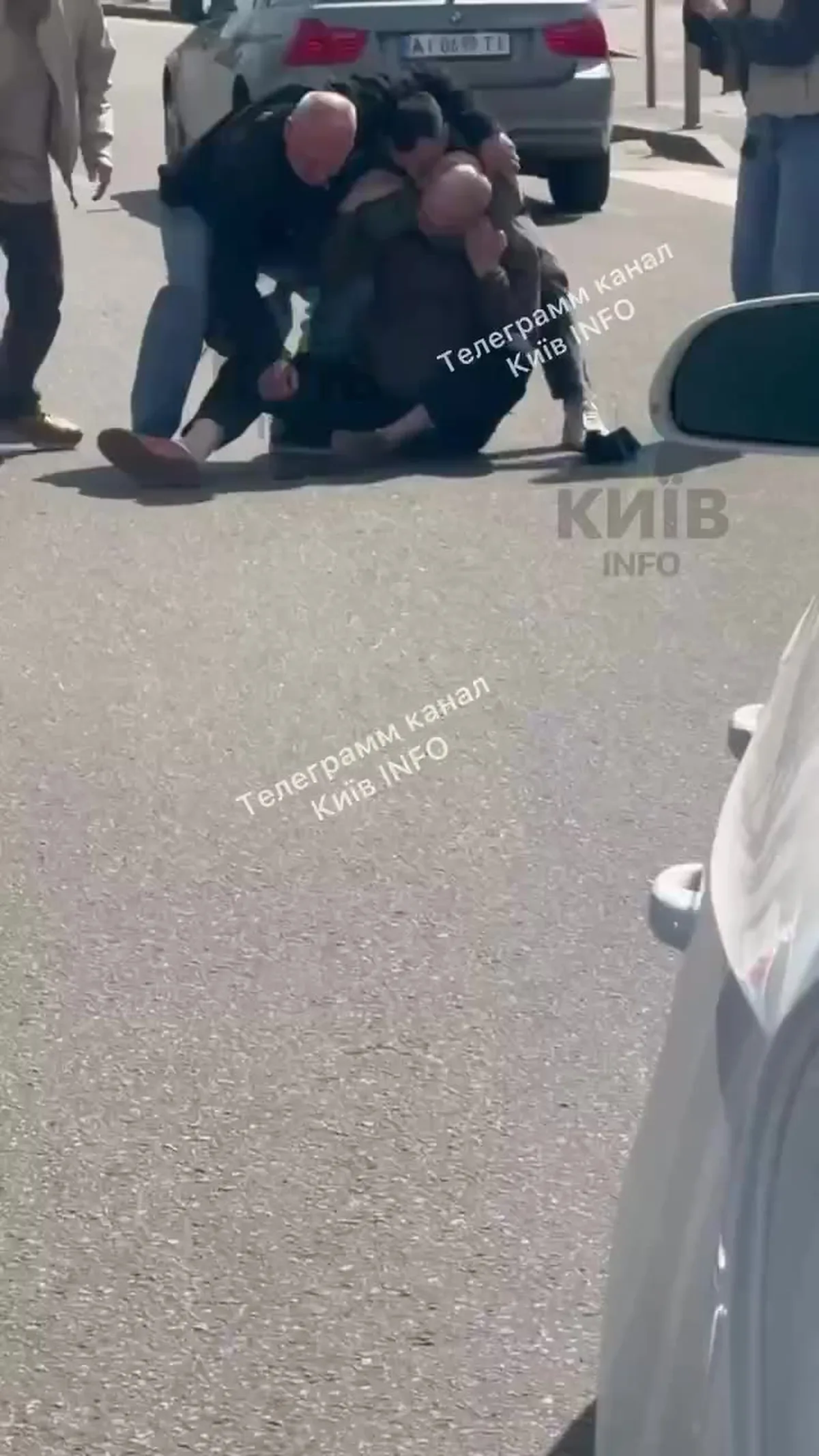 Люди на асфальті біля припаркованих автомобілів