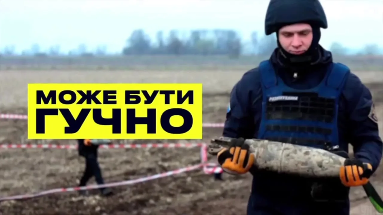 Сапер у захисному костюмі тримає снаряд на полі