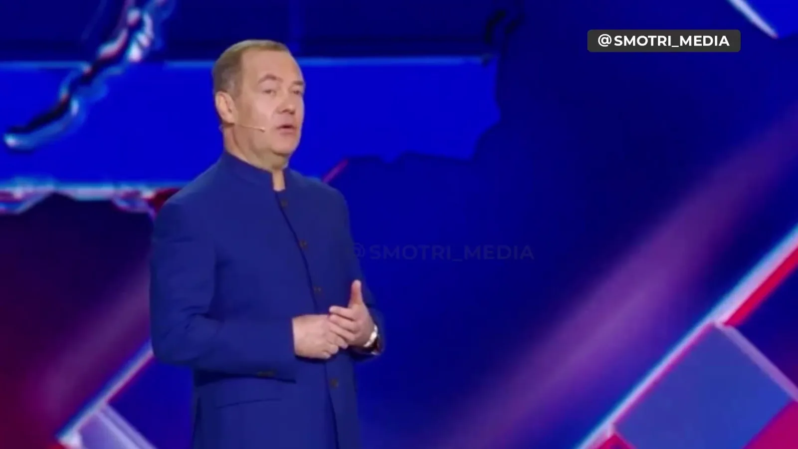 Чоловік виступає на сцені з синім фоном