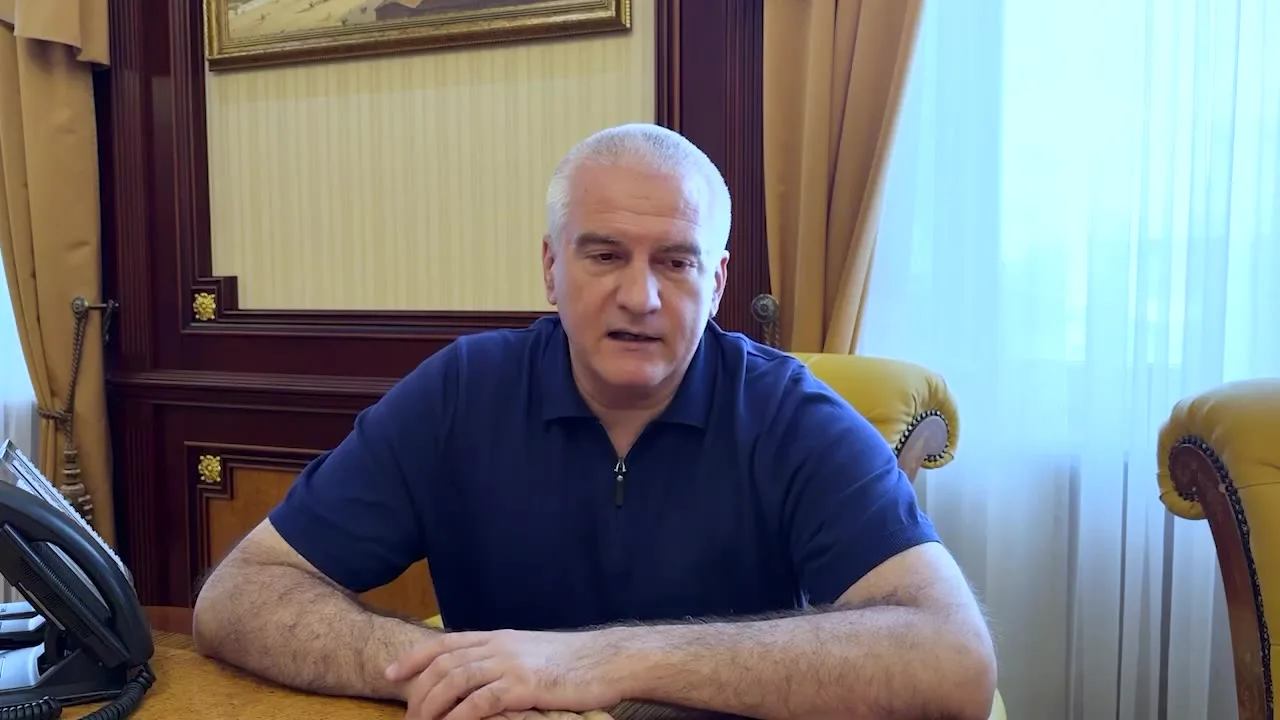 Чоловік у синій футболці за столом в офісі