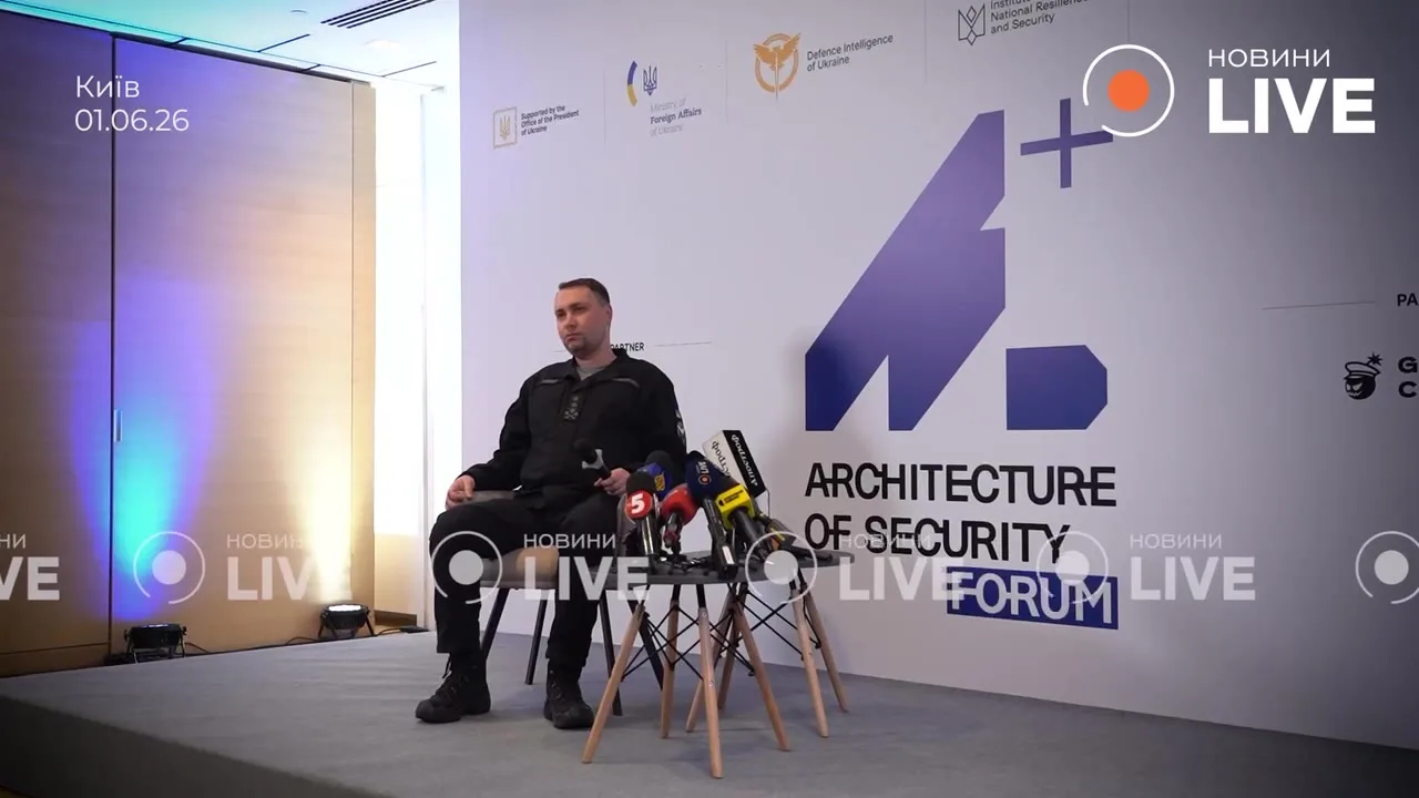 Чоловік сидить за столом з мікрофонами на форумі