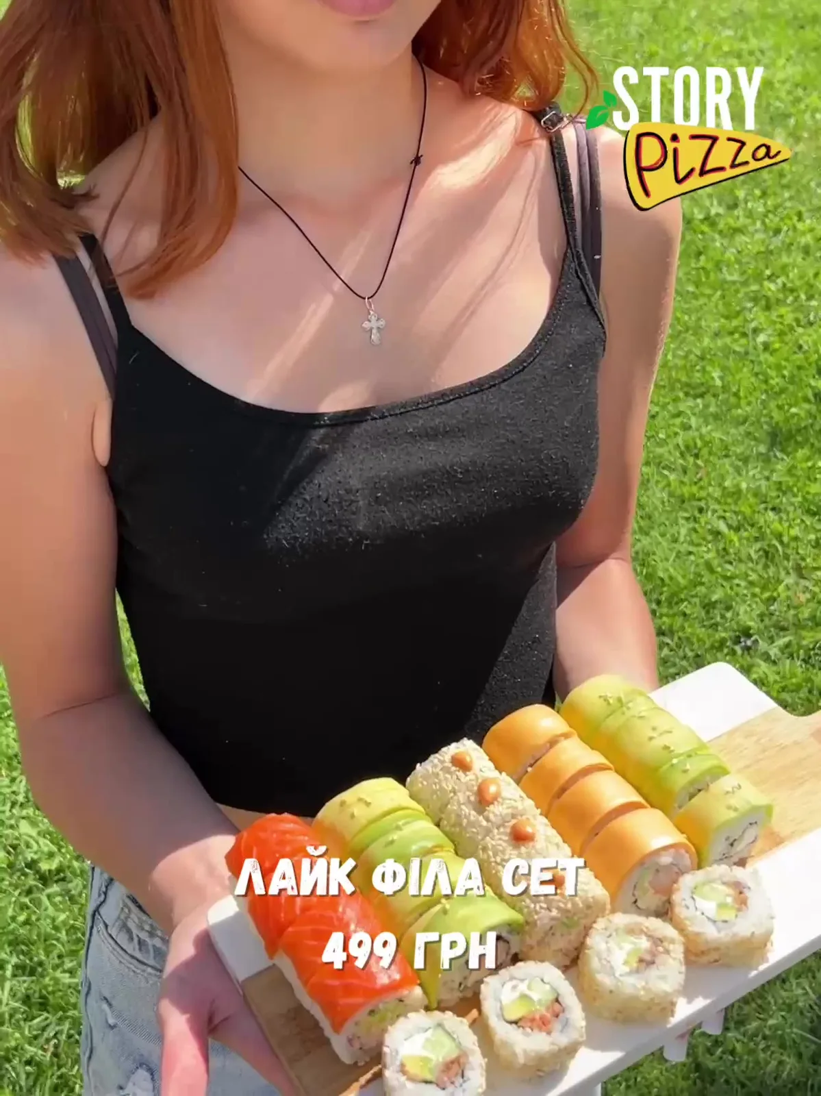Жінка тримає коробку з піцою на траві