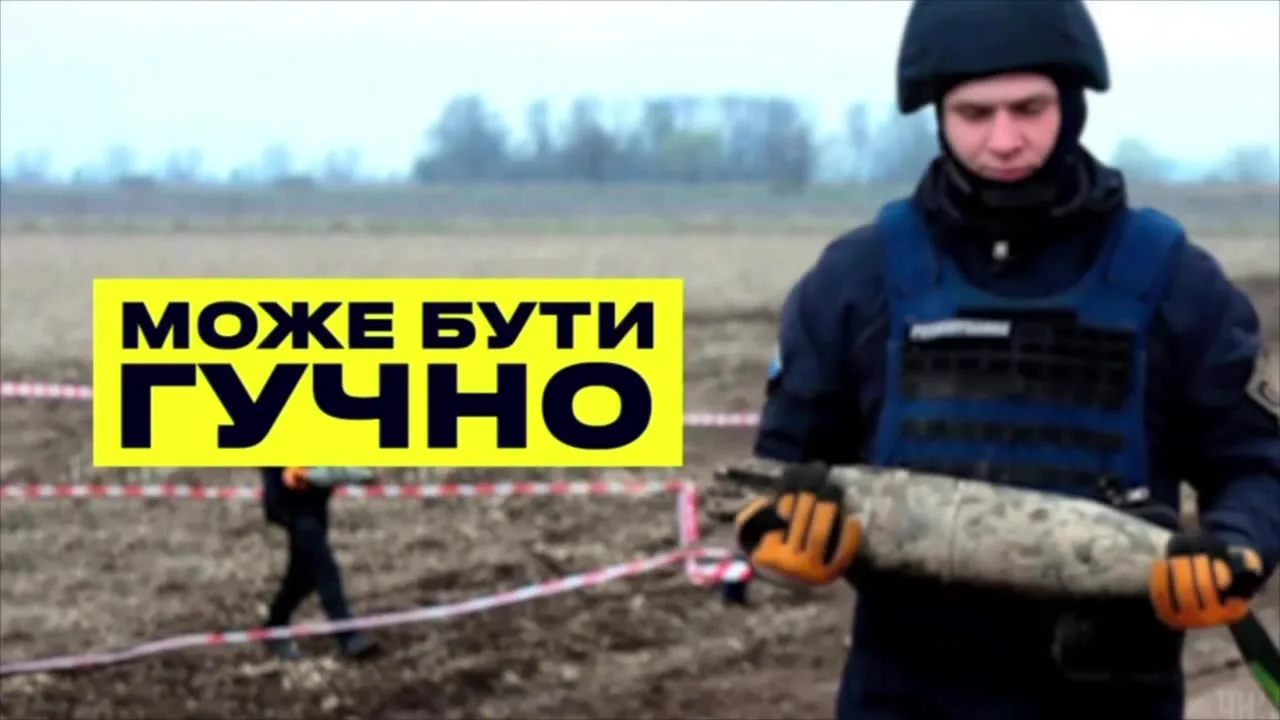 Військовослужбовець у захисному спорядженні тримає снаряд на полі