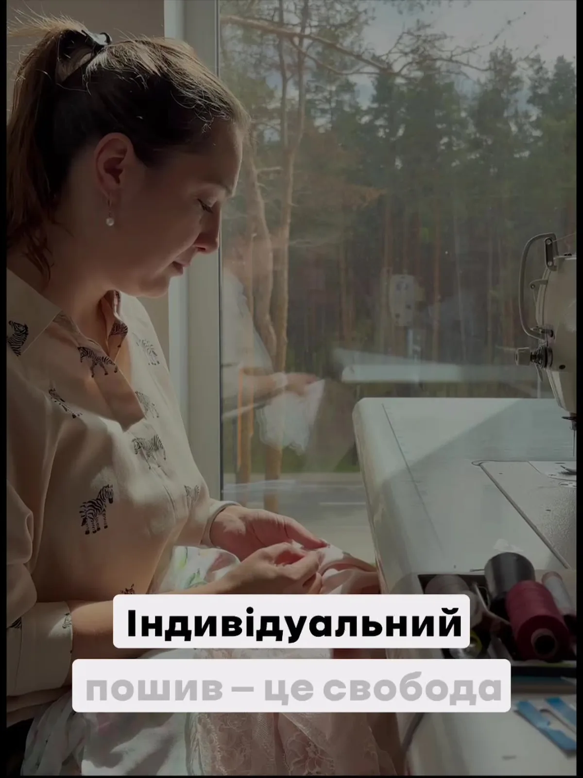 Жінка за швейною машиною шиє одяг у майстерні