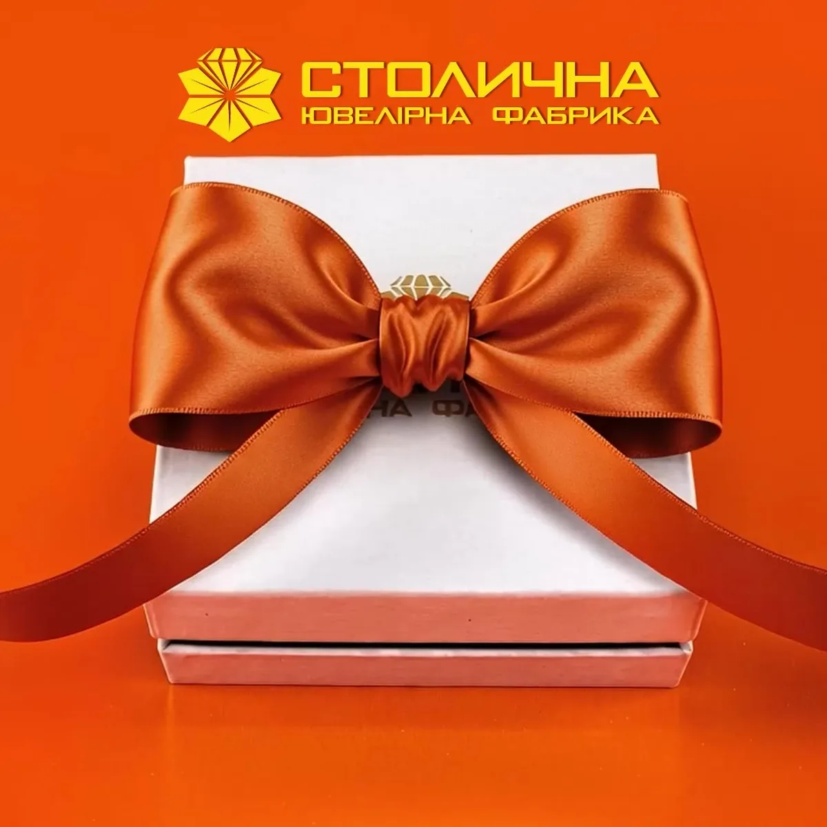 Біла коробка з помаранчевою стрічкою та бантом