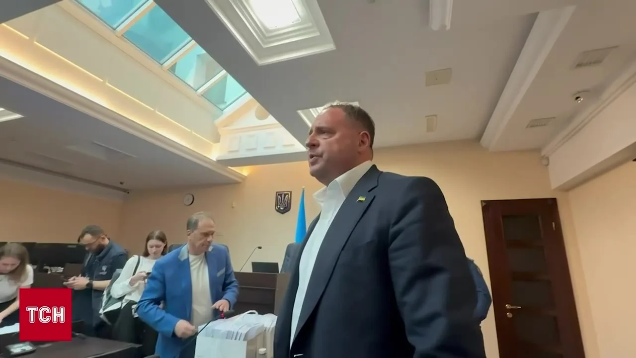Чоловік у темному костюмі стоїть у залі засідань