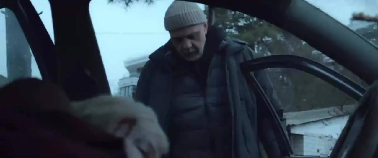 Чоловік у сірій шапці біля автомобіля