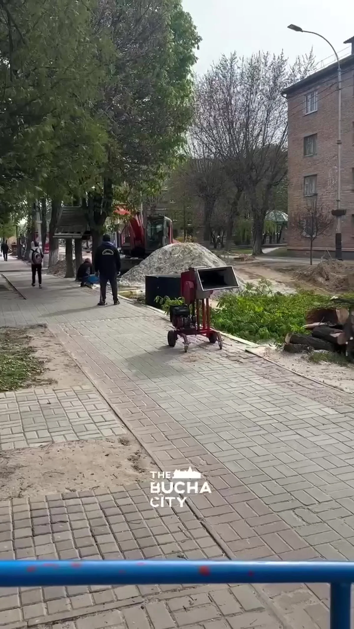 Жінка з парасолькою на тротуарі біля спиленого дерева