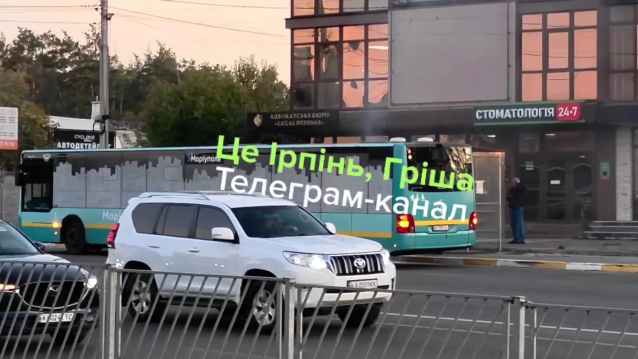 Білий позашляховик припаркований на вулиці біля будівель