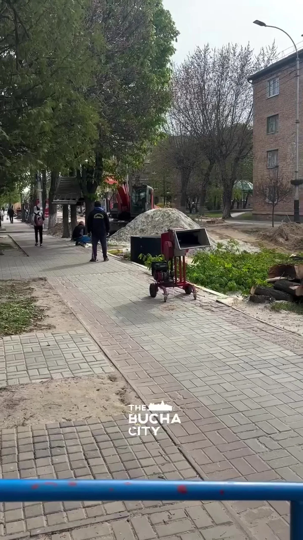 Вулиця з деревами, люди біля кіоску на тротуарі