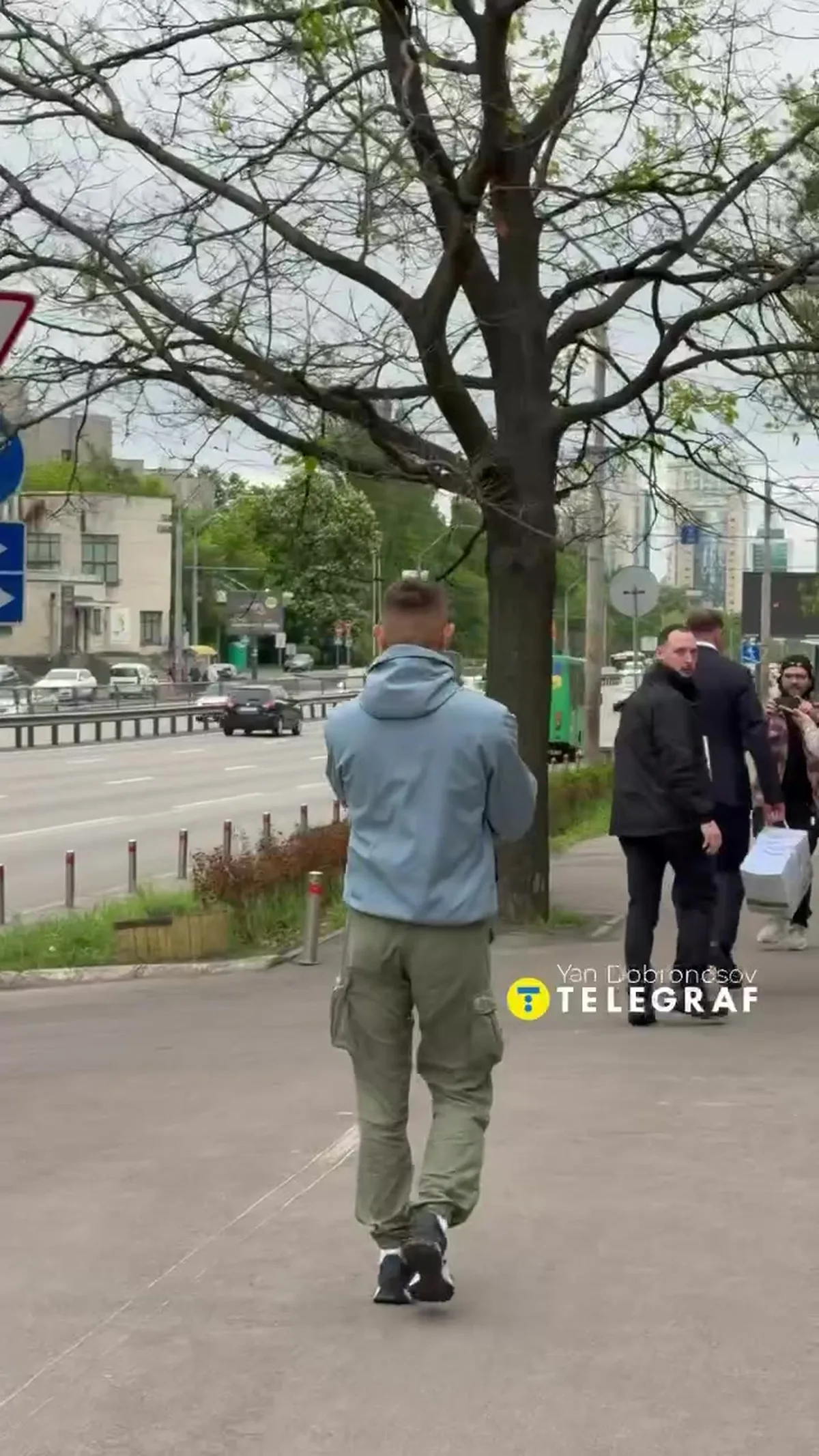 Чоловік у сірій куртці біжить по вулиці міста