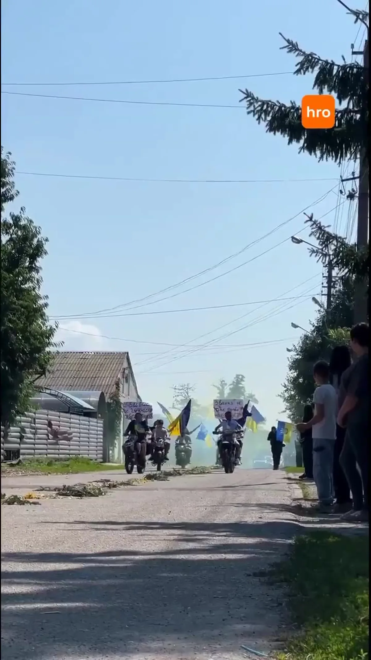 Люди з українськими прапорами на сільській вулиці