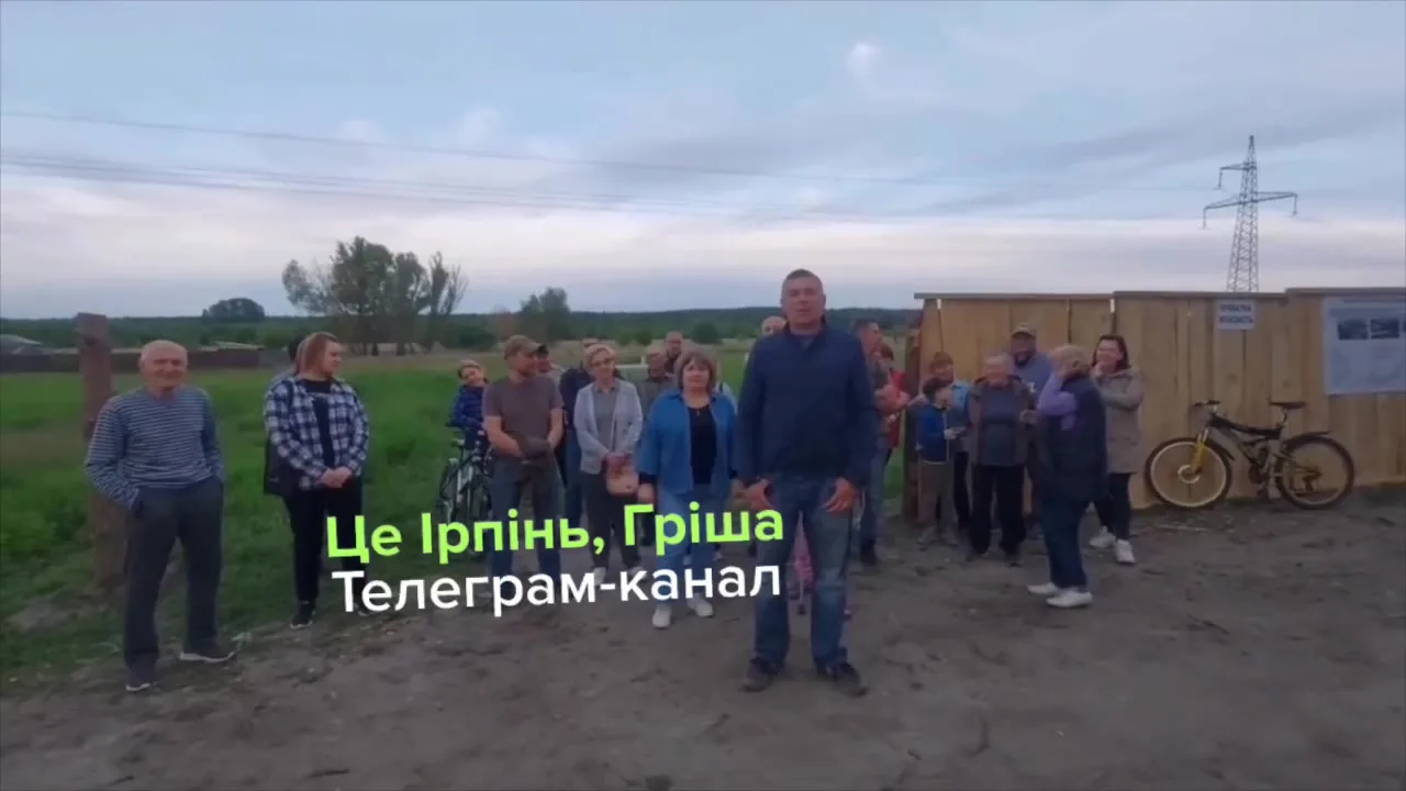 Група людей стоїть на полі біля паркану