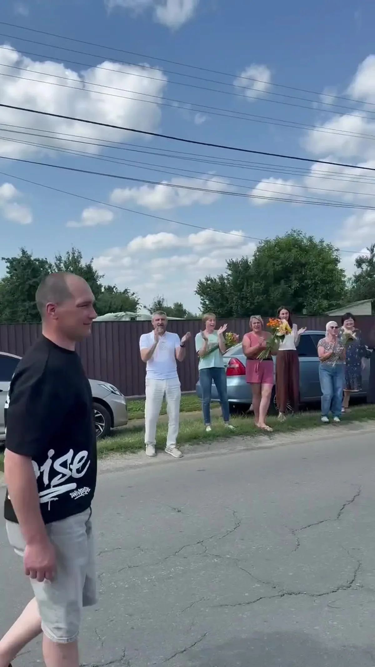 Чоловік у чорній футболці на вулиці серед групи людей