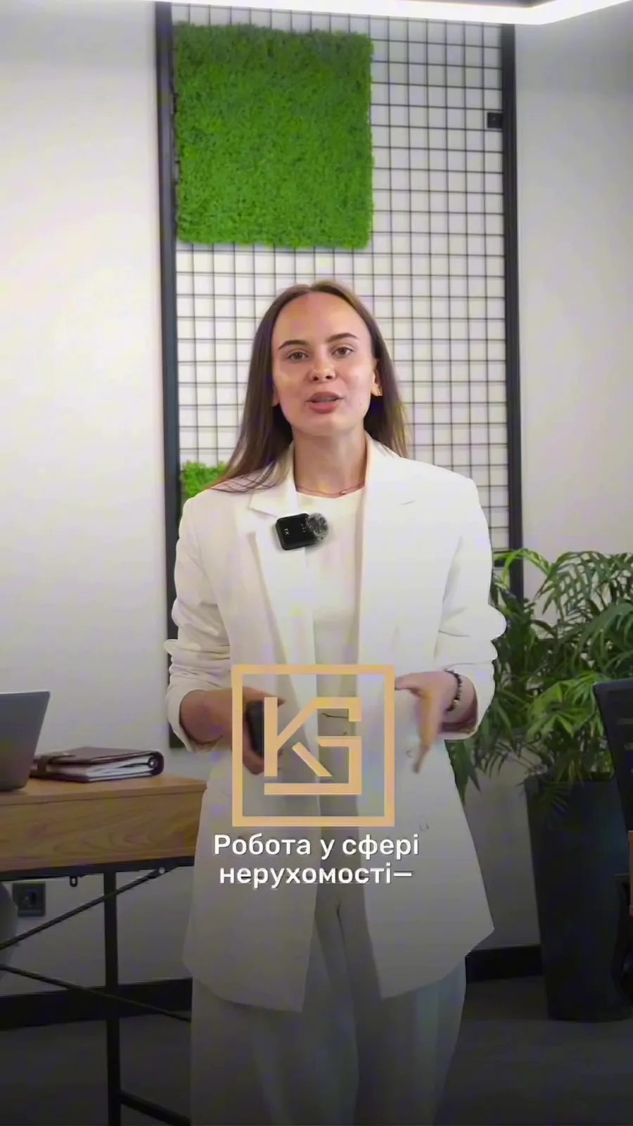Жінка в білому піджаку в офісі з зеленою стіною