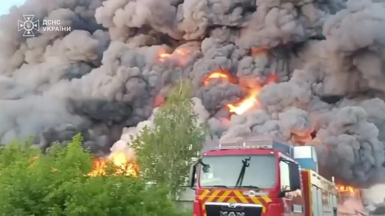 Пожежна машина біля палаючого складу з густим димом