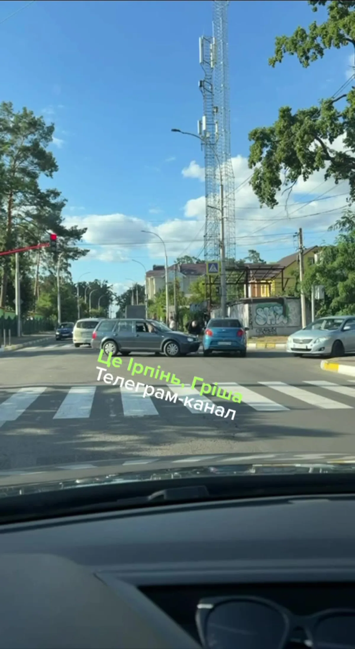 Перехрестя вулиць з припаркованими автомобілями та телевежею