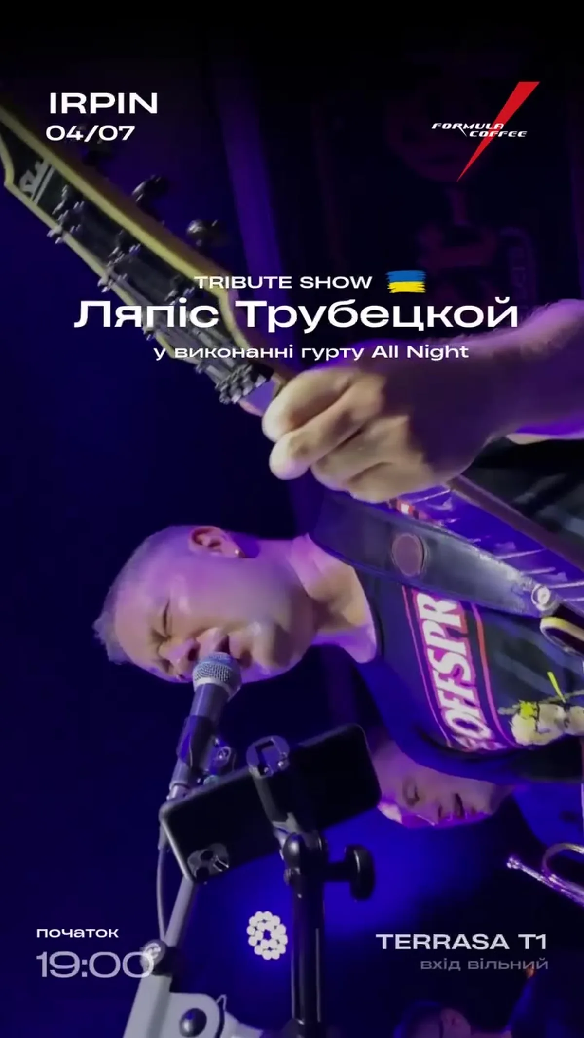 Музикант з мікрофоном на сцені під фіолетовим світлом
