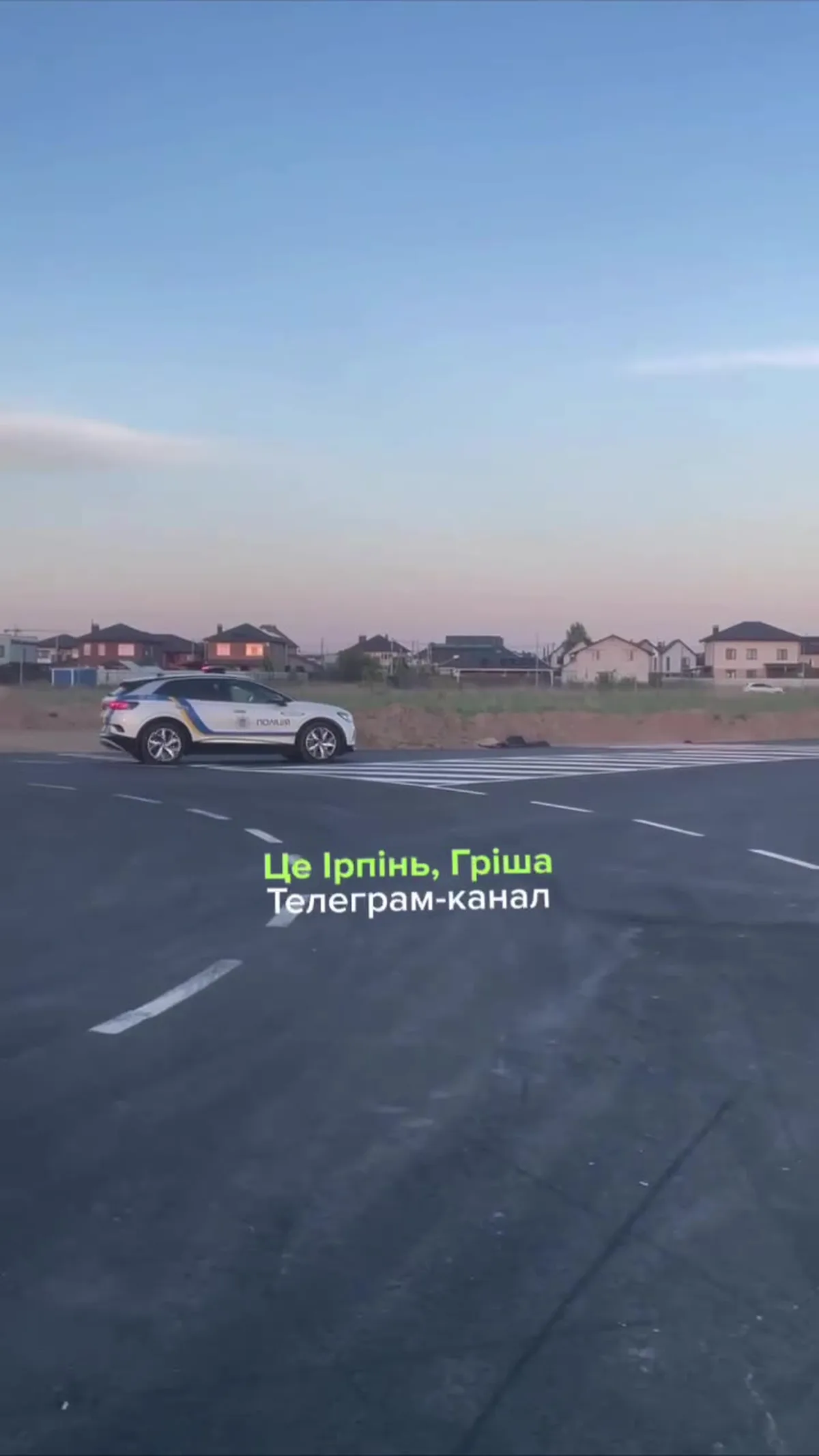 Білий автомобіль на дорозі біля житлового комплексу