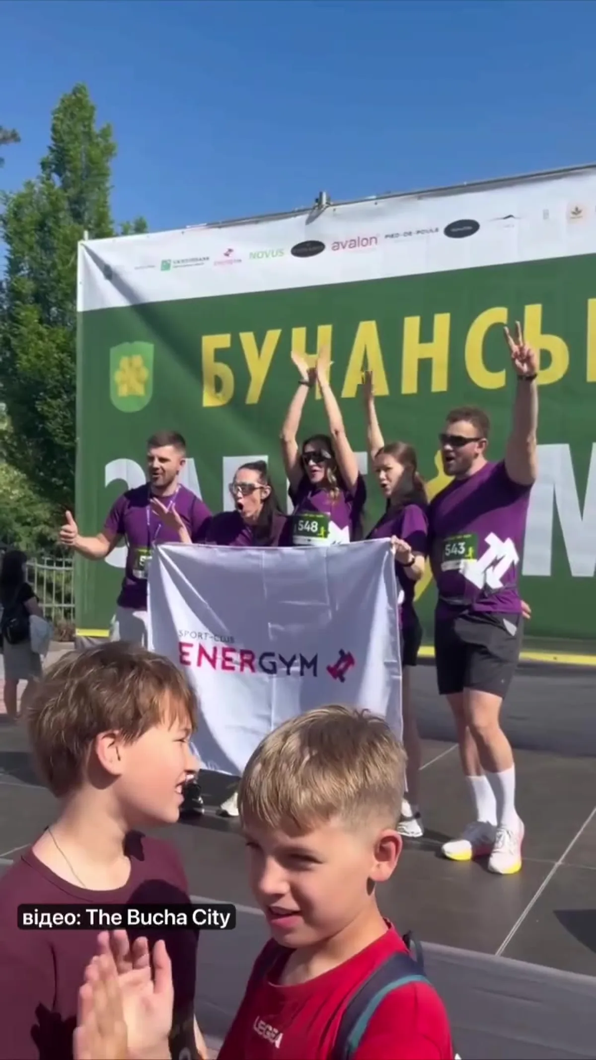 Учасники забігу з прапором організації на фоні автомобіля