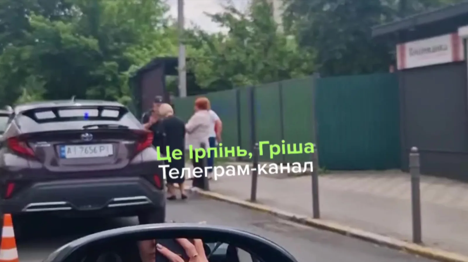 Два автомобілі на вулиці, люди біля машин, дорожні конуси