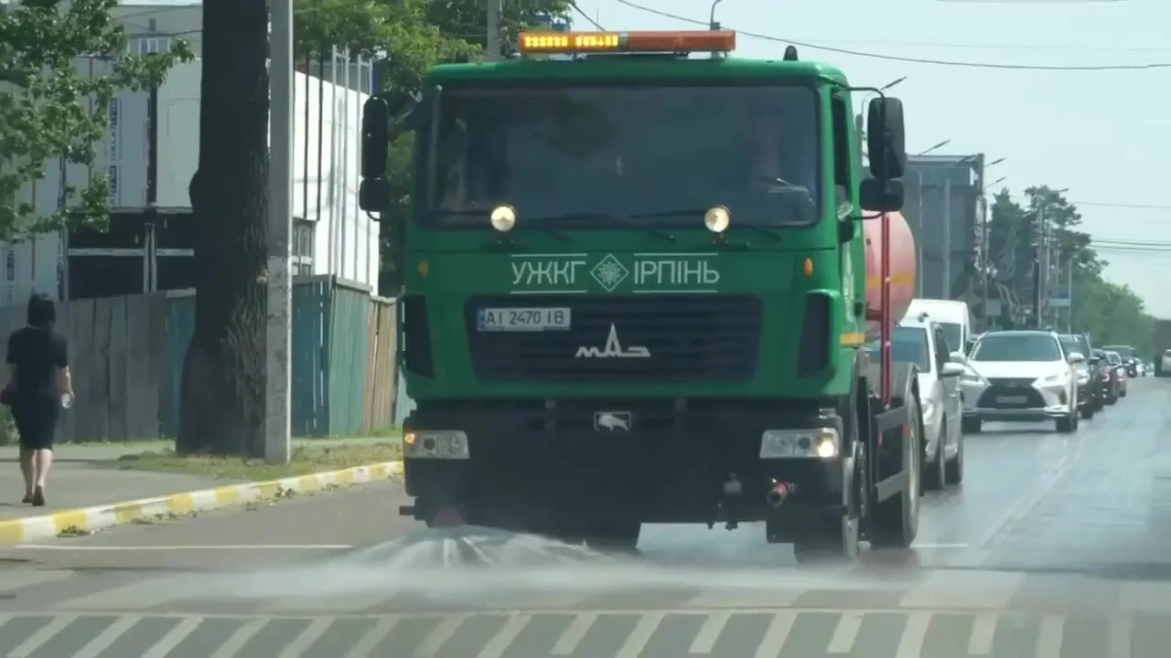 Зелений комунальний автомобіль поливає дорогу в спеку