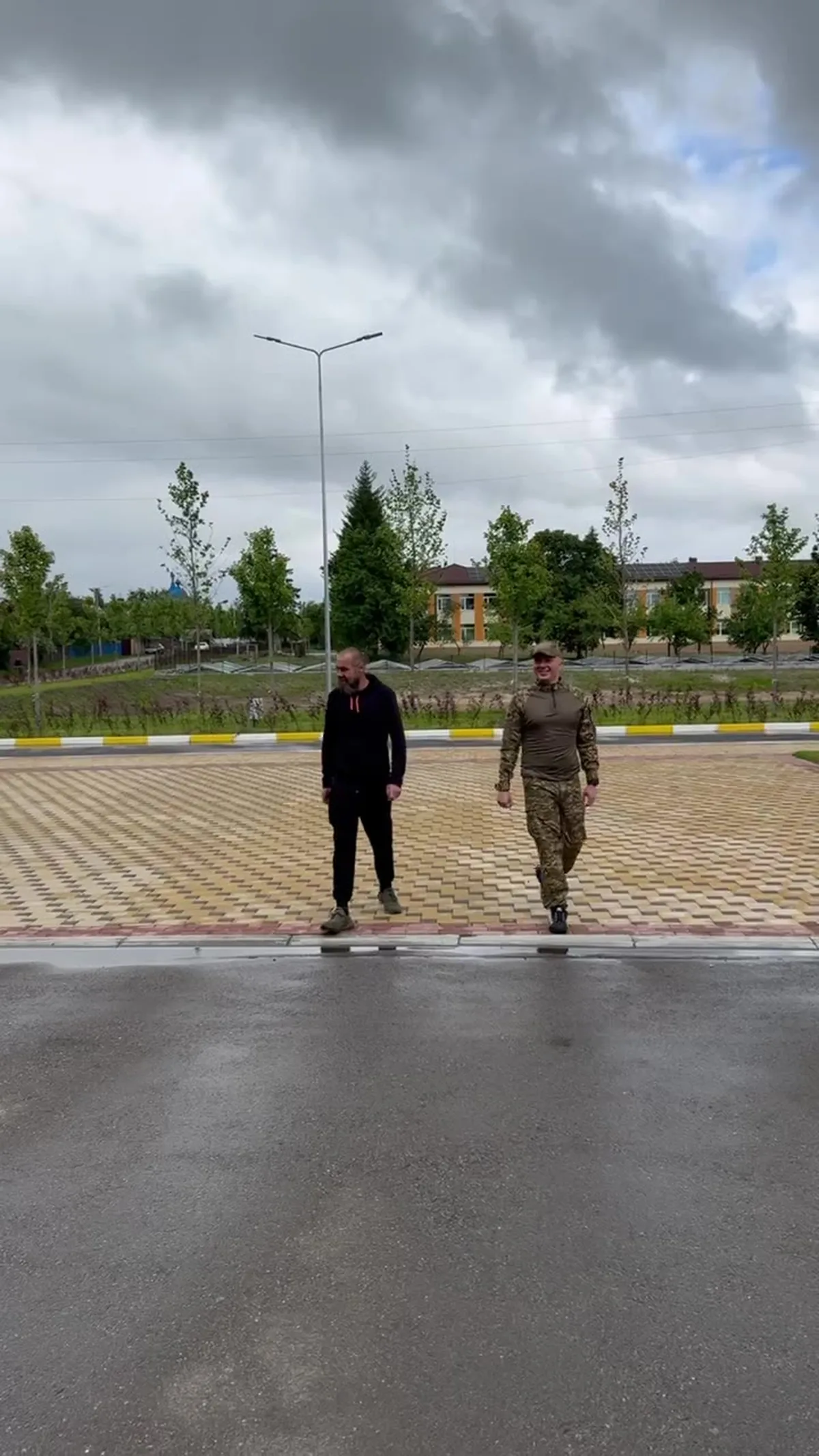 Двоє чоловіків стоять на мощеній площі біля озера