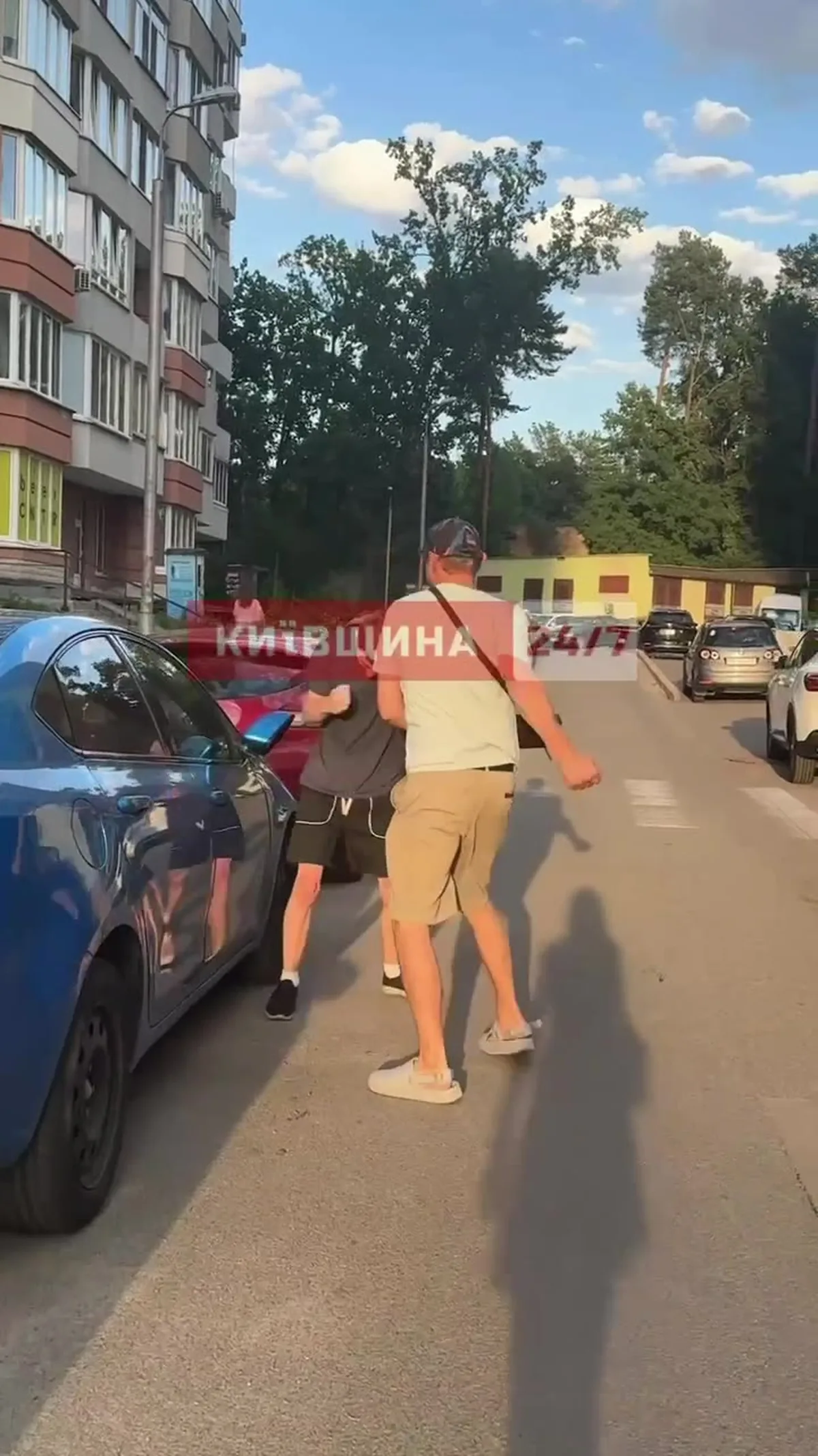 Чоловік з червоним прапором біля припаркованого автомобіля на вулиці