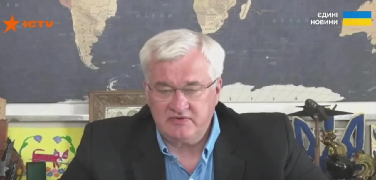 Чоловік середнього віку в окулярах біля карти світу