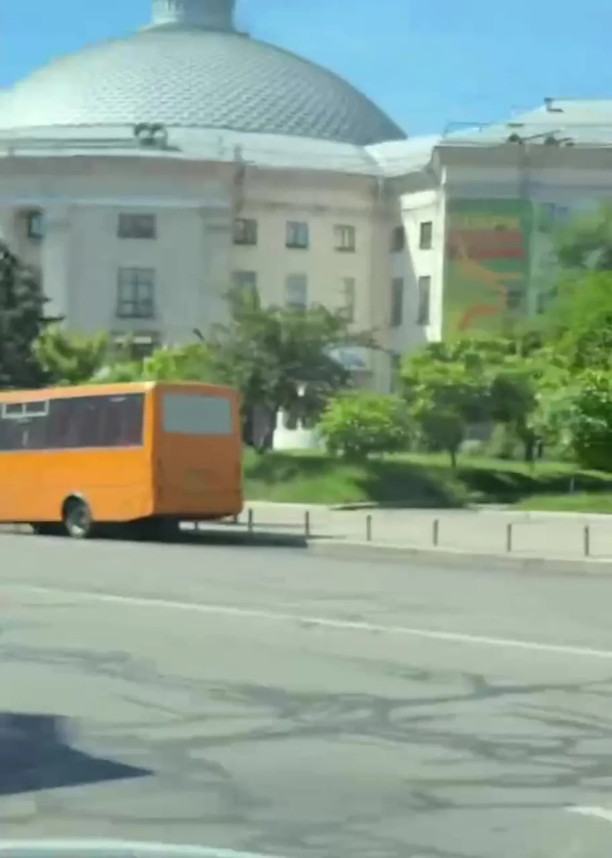 Помаранчевий мікроавтобус на вулиці біля будівлі з куполом