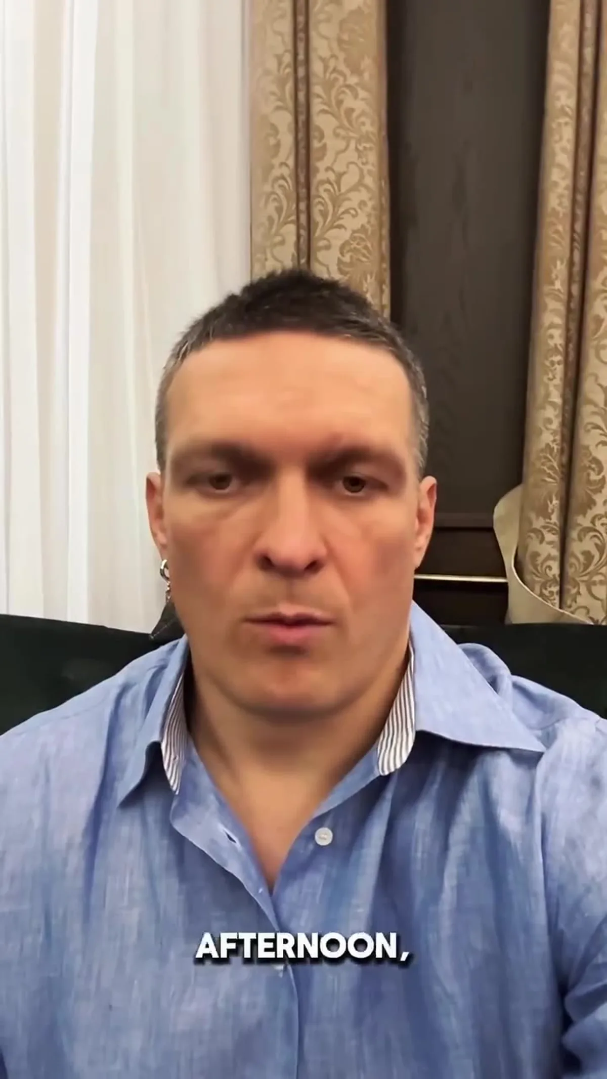 Чоловік у блакитній сорочці на фоні штор
