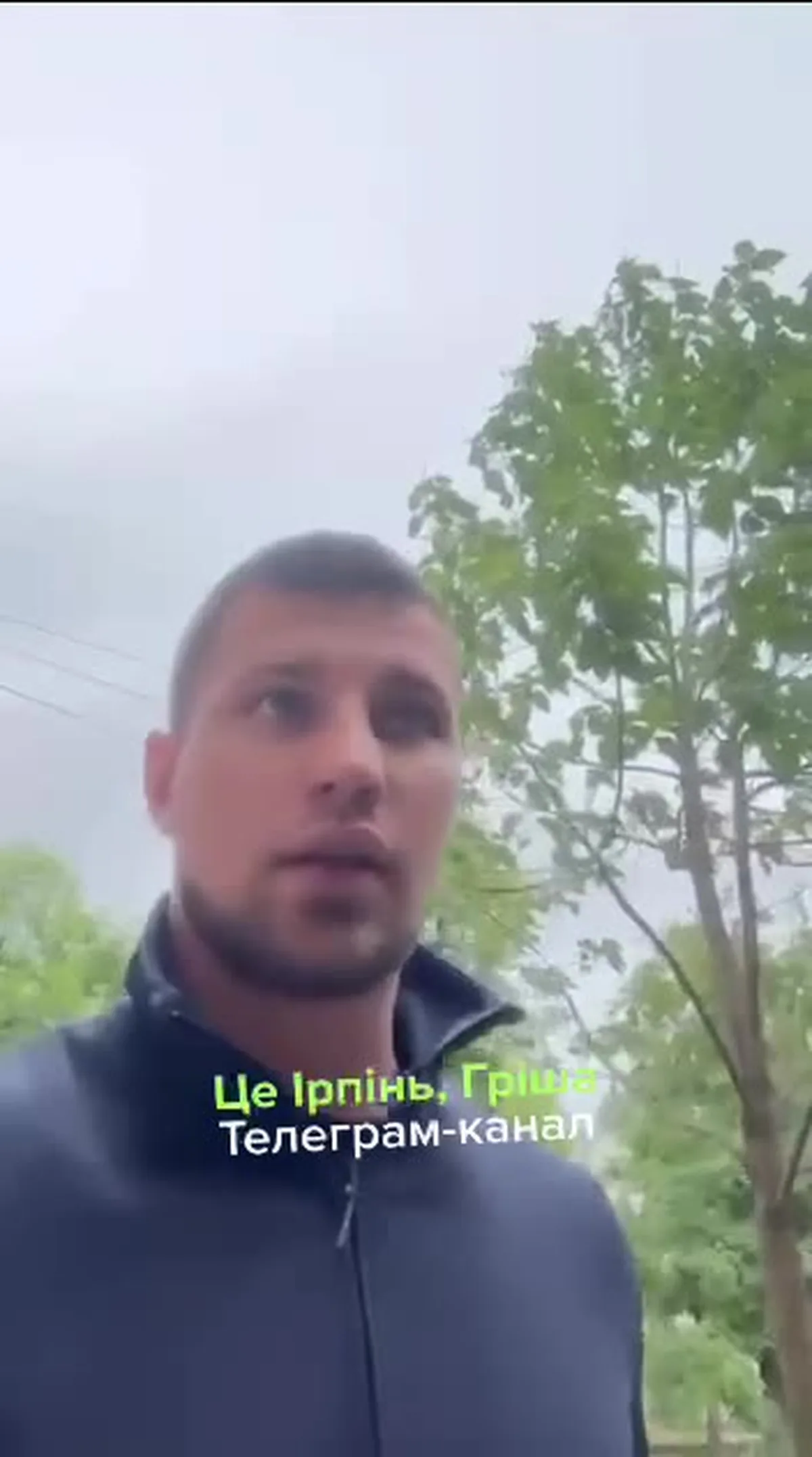 Чоловік у темній куртці на фоні дерев та неба