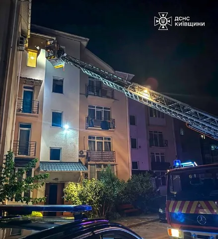 Пожежна машина біля багатоповерхового будинку вночі