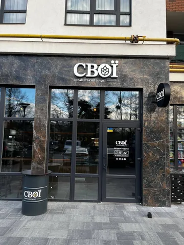 Фасад магазину СВОЇ з темною облицюванням та великими вікнами