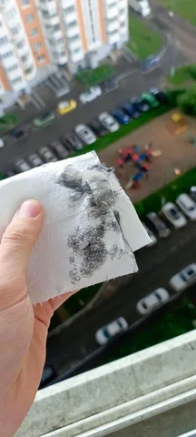 Рука тримає папір з чорним нальотом від дощу