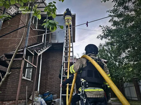 Рятувальник піднімається драбиною до пошкодженої будівлі
