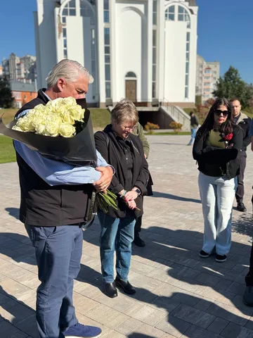 Люди з квітами біля білої церкви на площі