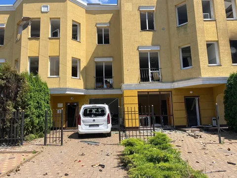 Пошкоджена будівля з вибитими вікнами та білий автомобіль