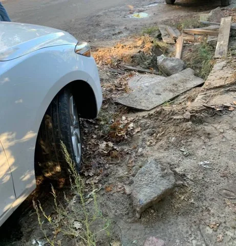 Білий автомобіль провалився в яму на вулиці